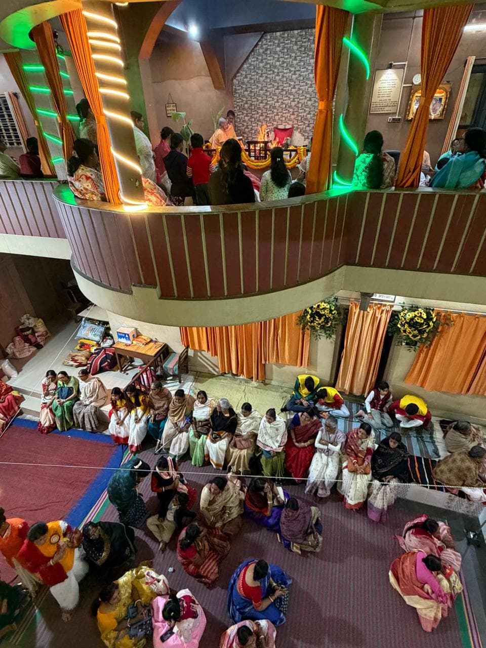 A view from above of a hall filled with seated people, with more gathered on a curved upper gallery