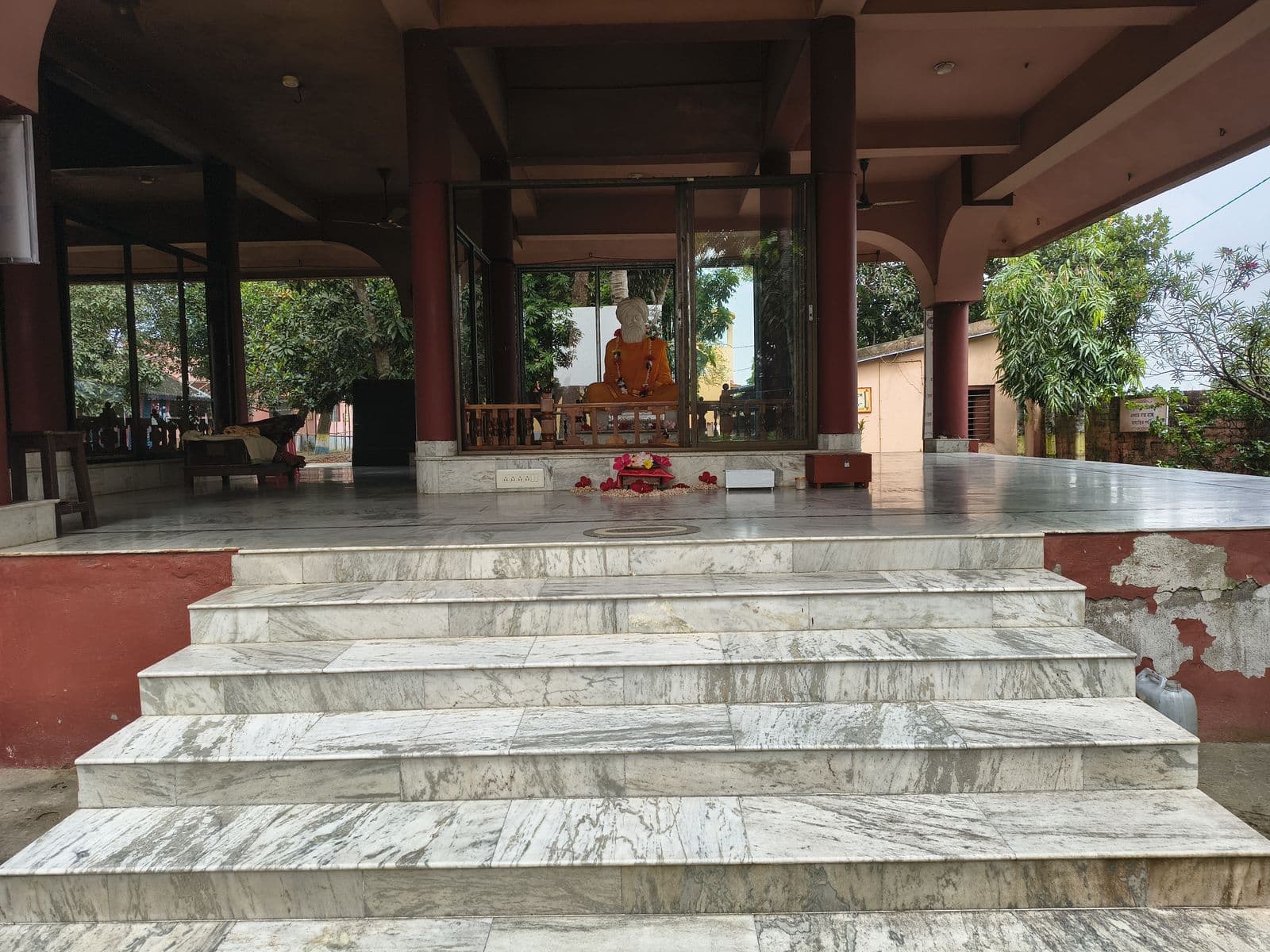 Broad marble steps leading up to an open temple hall with a seated statue behind glass