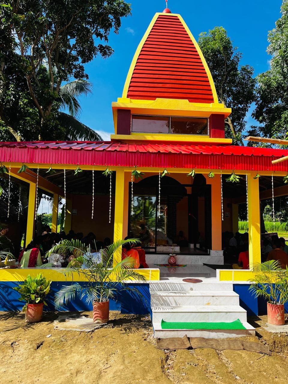 A temple with a red-and-yellow tiered spire and an open pillared hall, with steps up to its entrance