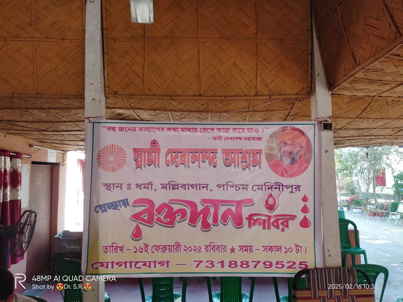 A blood donation camp: donors resting on beds in a hall, with a banner on the wall