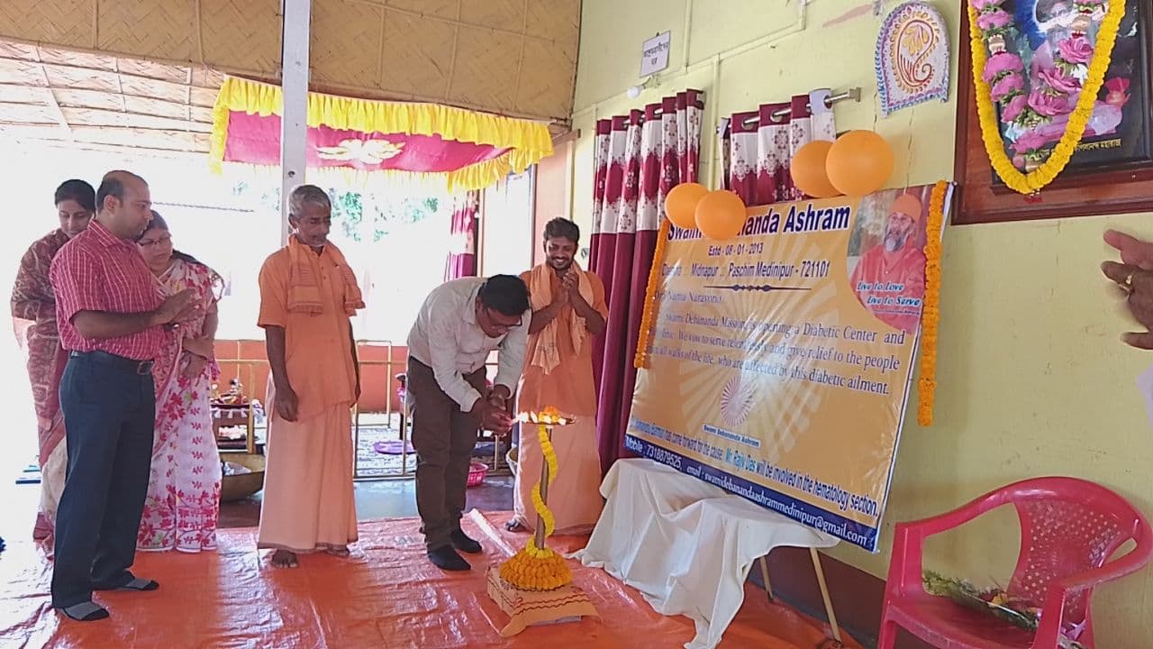 Monks and guests gathered beside a garlanded lamp and a banner