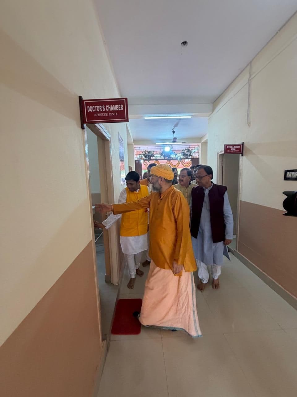 A monk in saffron walking along a corridor lined with signboards