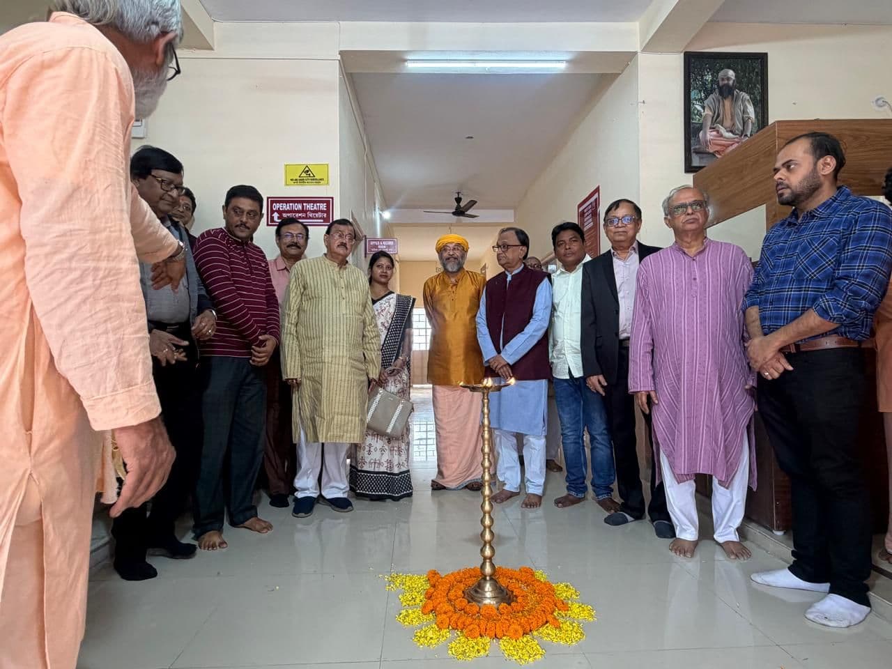 Guests standing in a corridor around a tall brass lamp set in a ring of marigolds