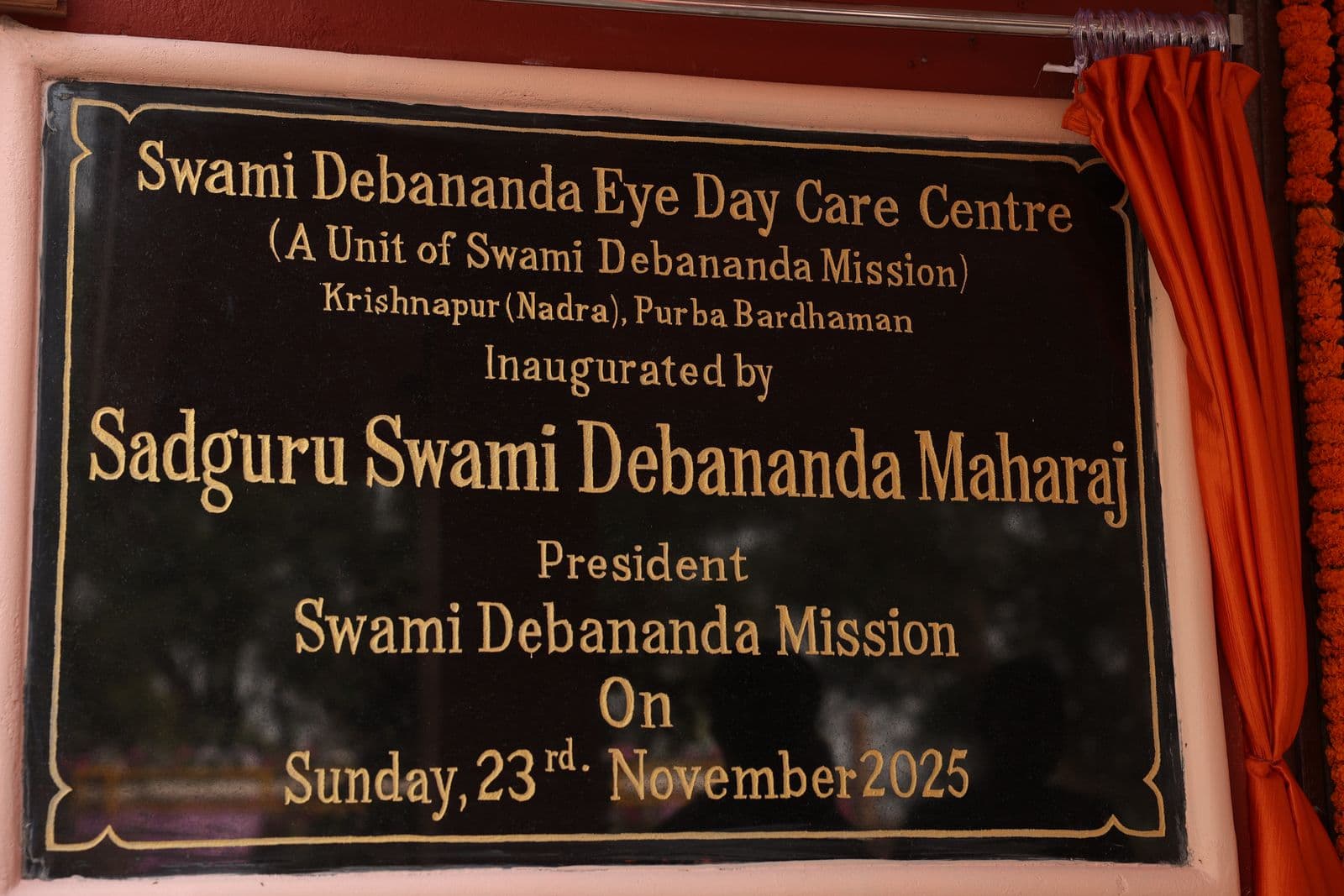 The inauguration plaque of the Swami Debananda Eye Day Care Centre, lettered in gold on black