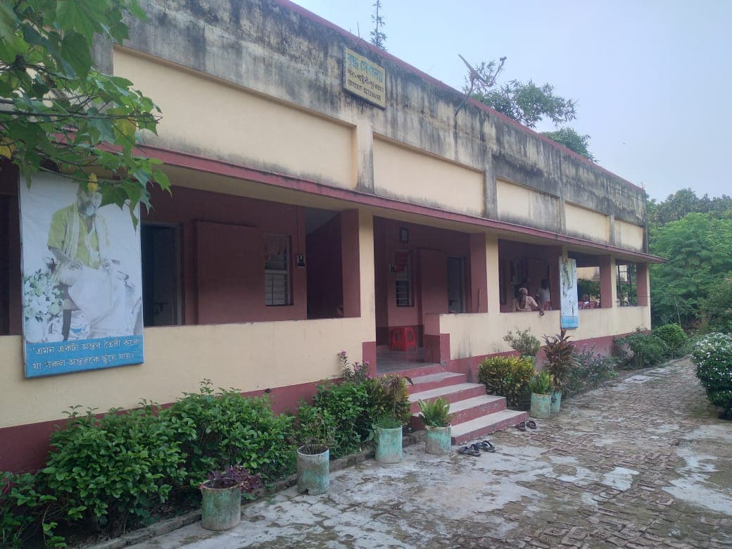 A long two-storey building with a covered veranda and potted plants lining its front path