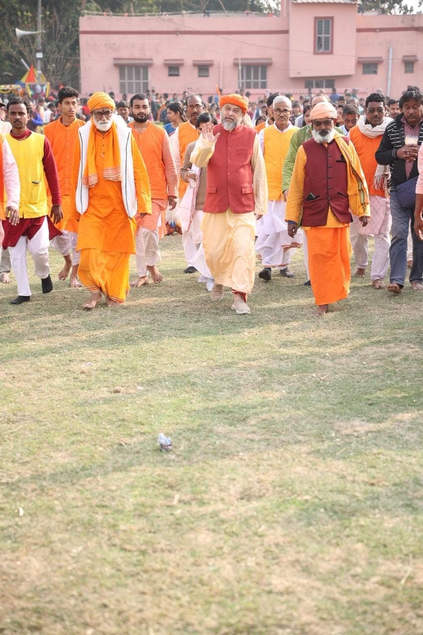 Swami Debananda Maharaj walking across a field with monks, followed by a large crowd