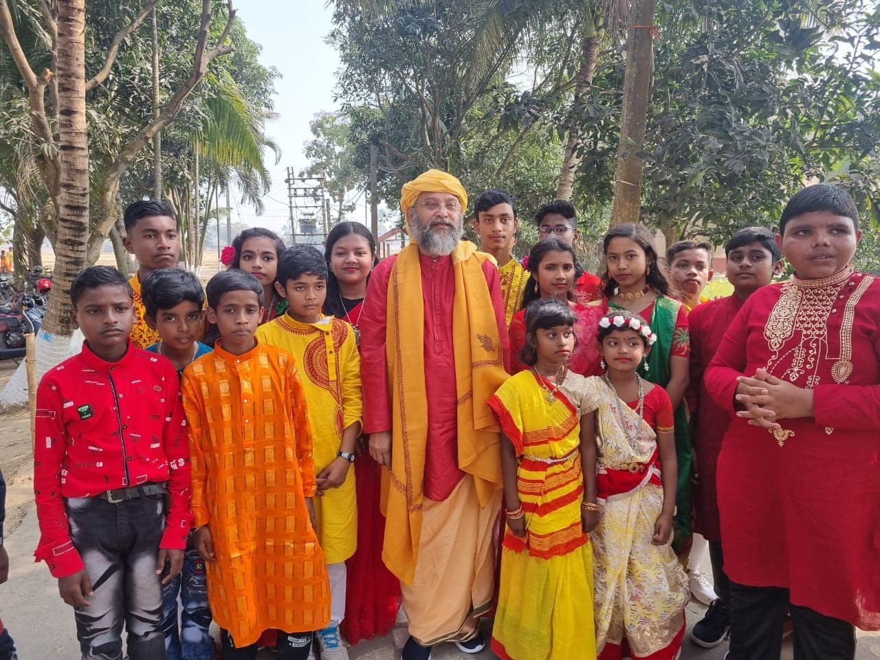 Swami Debananda Maharaj standing among children dressed in bright festive clothes