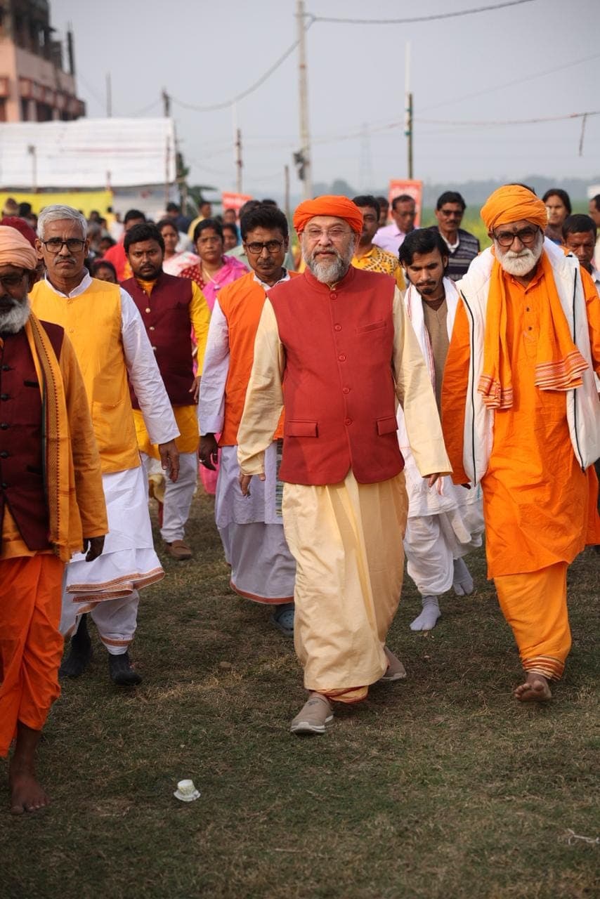 Swami Debananda Maharaj walking across a field among monks and devotees