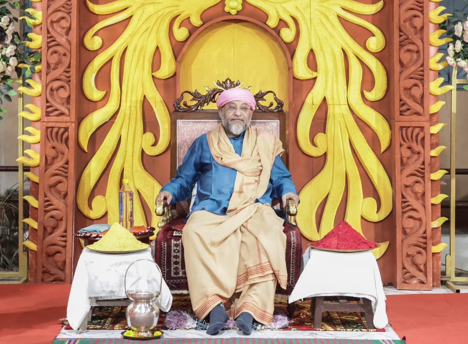 Swami Debananda Maharaj seated on a throne beneath a carved golden sunburst