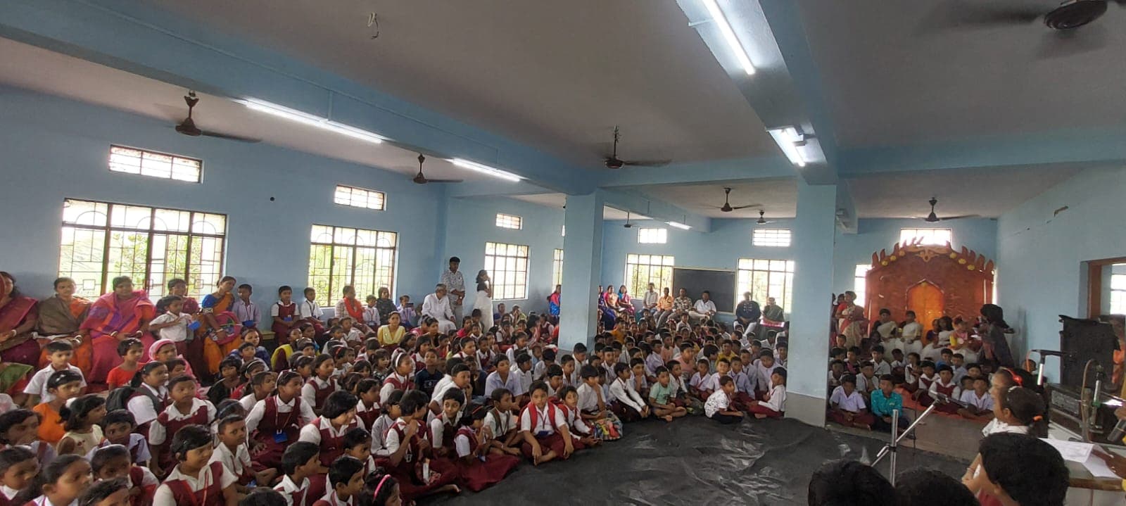 A wide hall filled with students seated on the floor